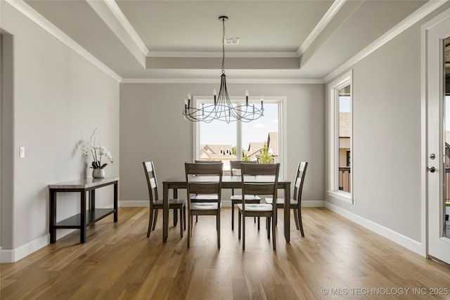 dining space featuring crown molding, a raised ceiling, and a chandelier