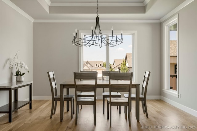 dining room with crown molding, a raised ceiling, hardwood / wood-style floors, and an inviting chandelier