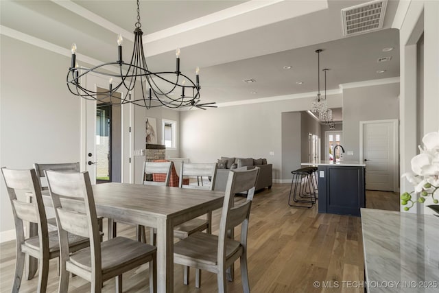 dining room featuring an inviting chandelier, a wealth of natural light, ornamental molding, and wood-type flooring