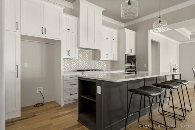 kitchen featuring white cabinetry, pendant lighting, backsplash, and a kitchen island with sink