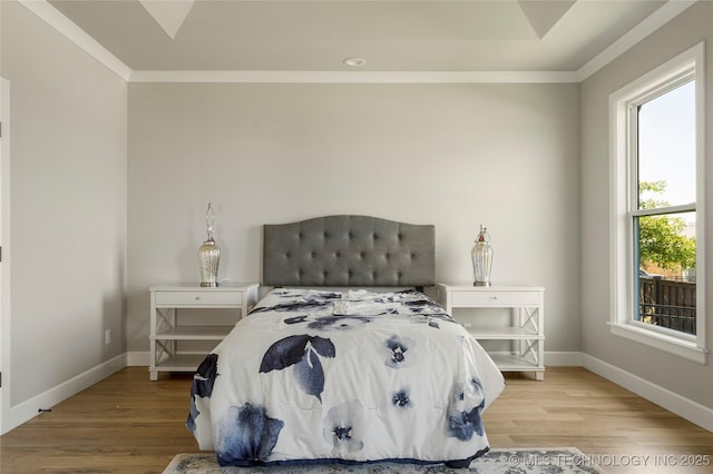 bedroom featuring ornamental molding, multiple windows, and light hardwood / wood-style flooring