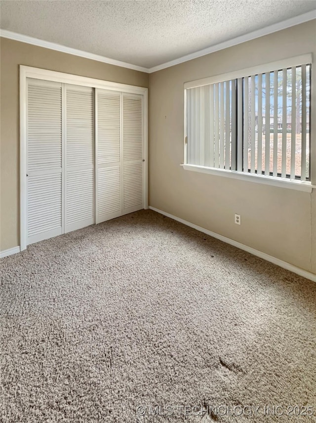 unfurnished bedroom with a textured ceiling, a closet, ornamental molding, and carpet flooring