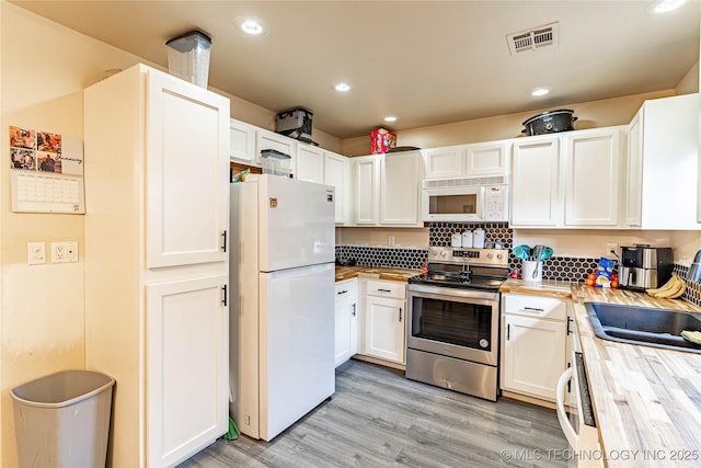 kitchen with white appliances, white cabinetry, decorative backsplash, sink, and light hardwood / wood-style flooring