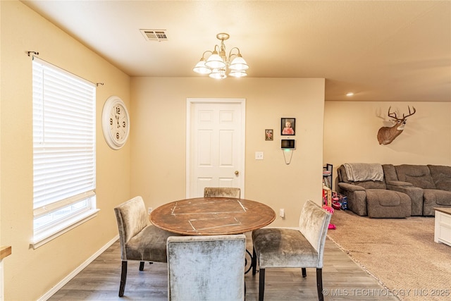 dining area with hardwood / wood-style flooring and a notable chandelier