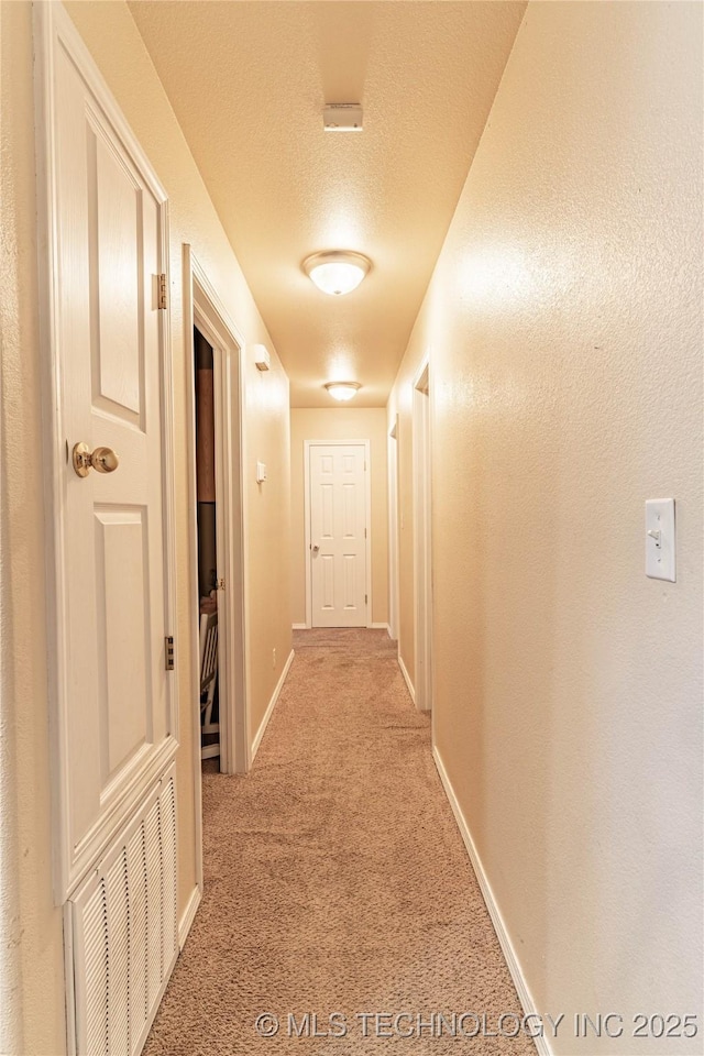 corridor featuring a textured ceiling and carpet flooring