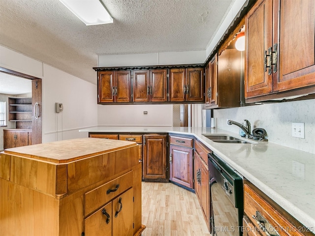 kitchen featuring dishwasher, a kitchen island, sink, light hardwood / wood-style flooring, and a textured ceiling