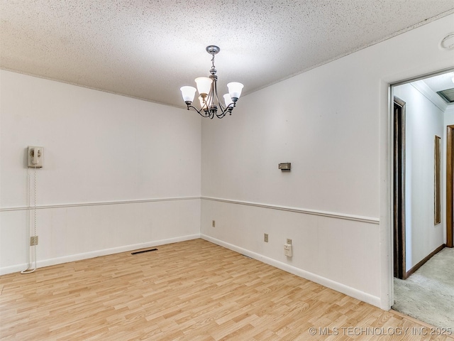 spare room with a chandelier, a textured ceiling, and hardwood / wood-style floors