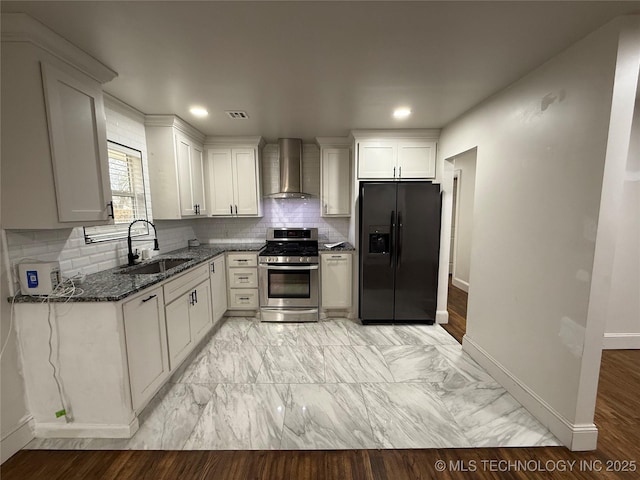 kitchen with gas stove, black fridge with ice dispenser, dark stone countertops, wall chimney exhaust hood, and sink