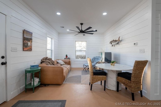 dining area featuring ceiling fan and wooden walls