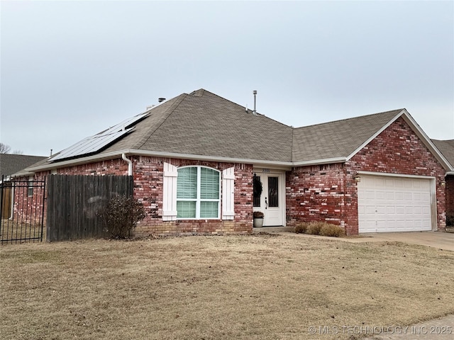 single story home with a garage, a front yard, and solar panels