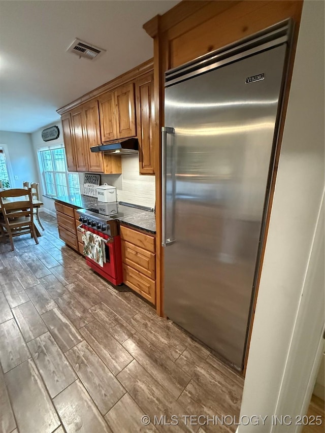 kitchen with hardwood / wood-style flooring, premium appliances, and decorative backsplash