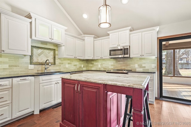 kitchen with white cabinets, a center island, stainless steel appliances, and dark stone counters