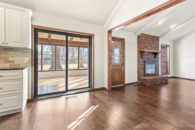 unfurnished living room with vaulted ceiling with beams, dark hardwood / wood-style floors, and a fireplace