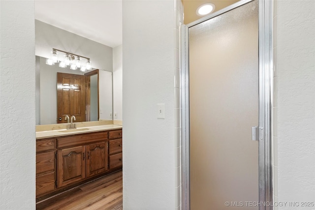 bathroom featuring vanity, hardwood / wood-style flooring, and a shower with shower door