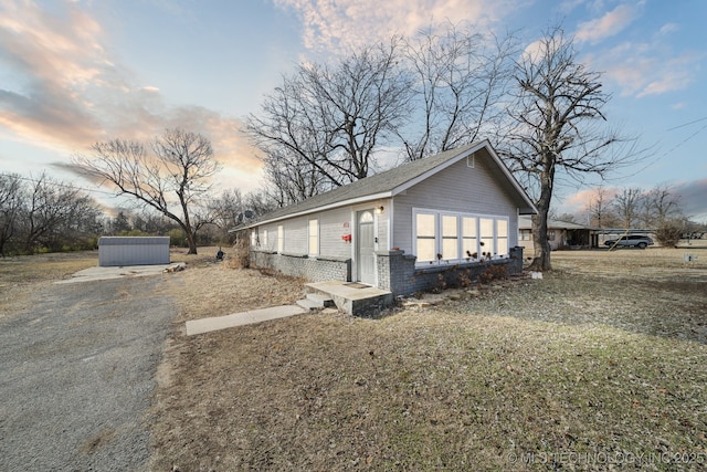 property exterior at dusk with a lawn and a storage unit