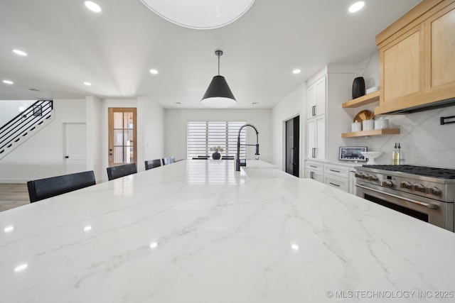 kitchen featuring a kitchen bar, light stone counters, and high end range