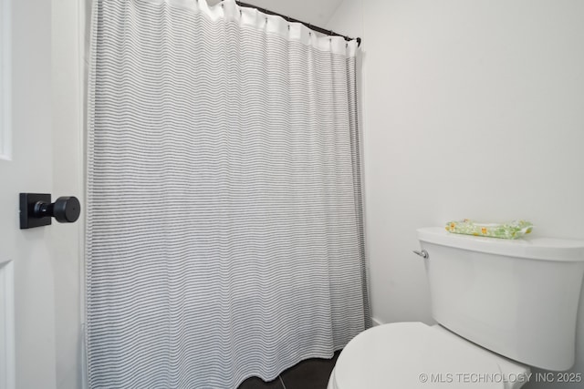 bathroom with curtained shower and toilet