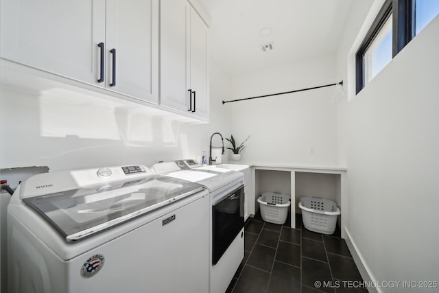 clothes washing area with washing machine and dryer, dark tile patterned flooring, sink, and cabinets