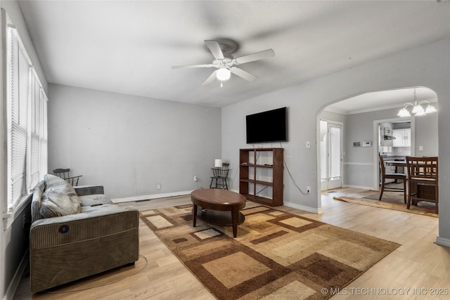 living room with light wood-type flooring, a healthy amount of sunlight, and ceiling fan with notable chandelier