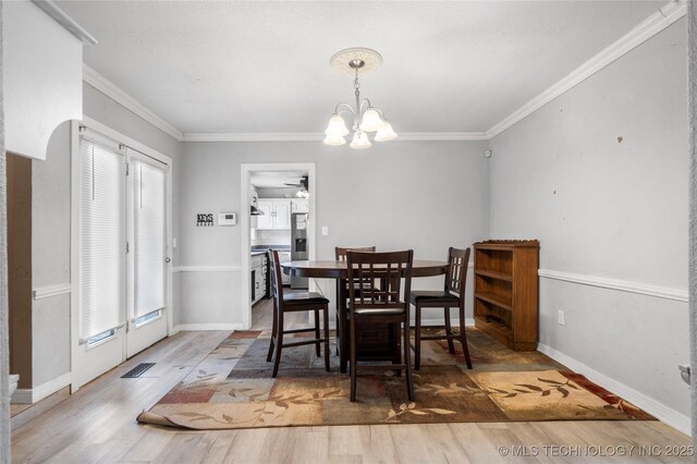 dining room with hardwood / wood-style flooring, crown molding, and ceiling fan with notable chandelier