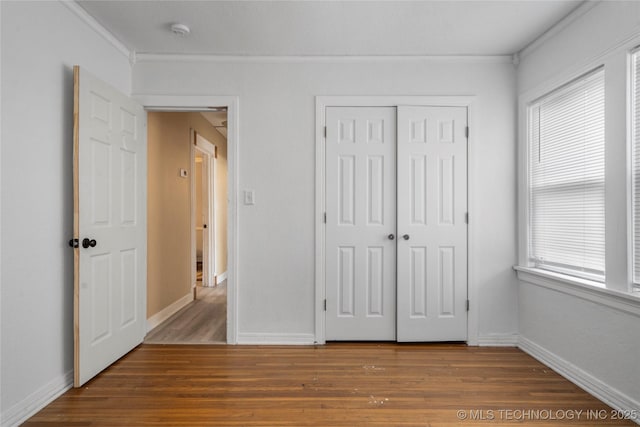 unfurnished bedroom featuring wood-type flooring, a closet, and ornamental molding