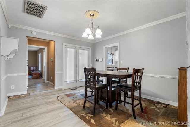 dining room with wood-type flooring, crown molding, and a chandelier