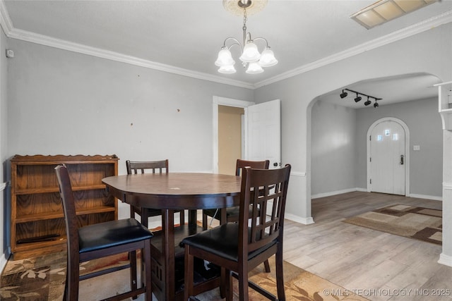 dining room with wood-type flooring, ornamental molding, and an inviting chandelier