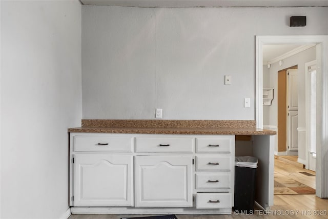 kitchen with white cabinets, ornamental molding, and light wood-type flooring