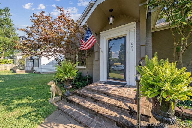 view of exterior entry with a yard