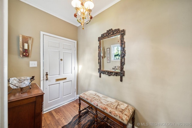 entryway with crown molding, an inviting chandelier, and hardwood / wood-style floors