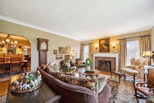 living room featuring a tiled fireplace, a wealth of natural light, ornamental molding, and hardwood / wood-style floors