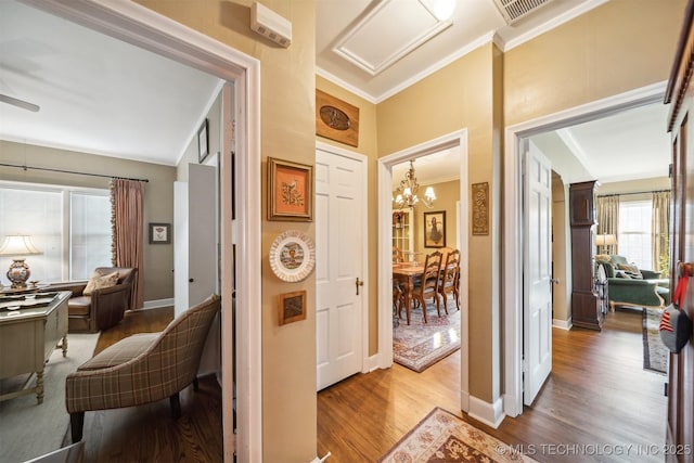 hallway featuring wood-type flooring, crown molding, and an inviting chandelier