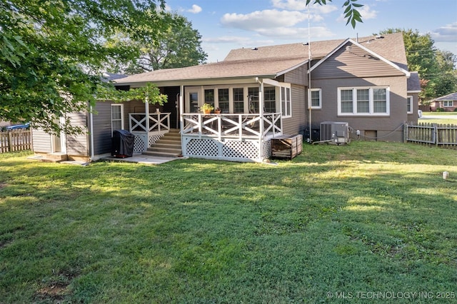 rear view of property with a yard, a sunroom, and central air condition unit