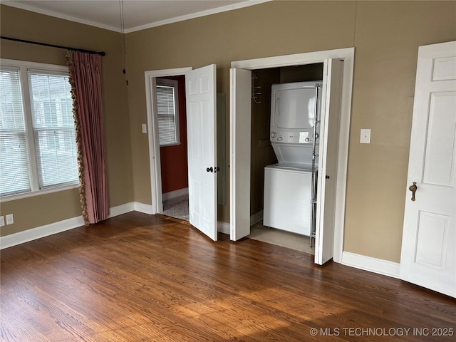 laundry room featuring dark wood-type flooring, stacked washer and clothes dryer, and crown molding