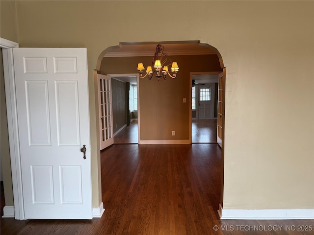 unfurnished dining area featuring crown molding, dark hardwood / wood-style floors, and a notable chandelier