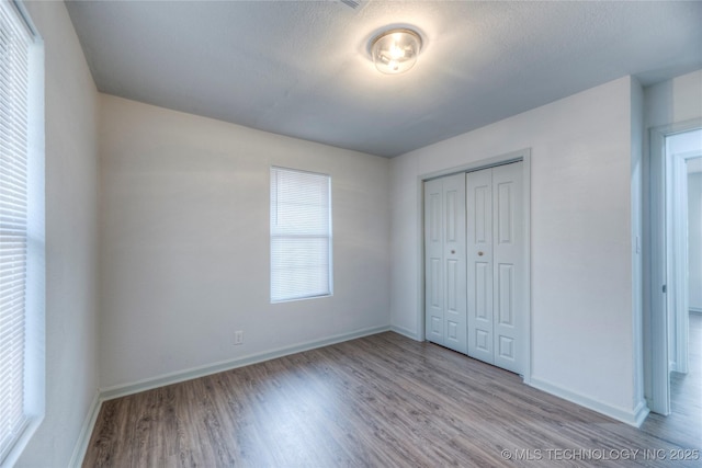 unfurnished bedroom with a textured ceiling, a closet, and light hardwood / wood-style floors