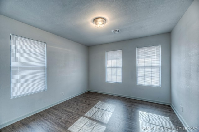 spare room featuring dark hardwood / wood-style floors and a textured ceiling