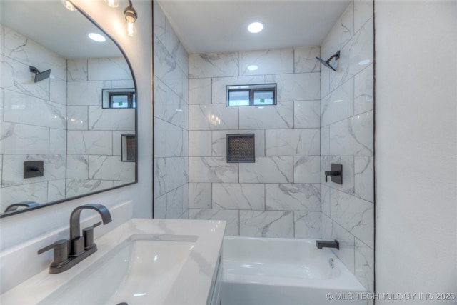 bathroom with tiled shower / bath combo and vanity