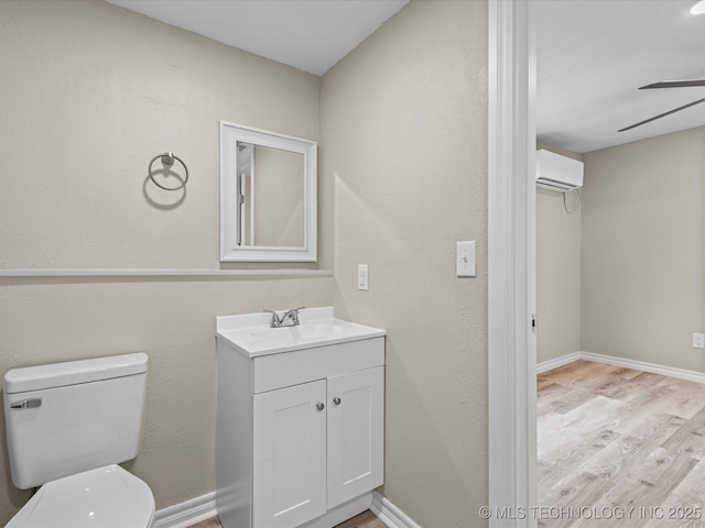 bathroom featuring an AC wall unit, vanity, ceiling fan, toilet, and hardwood / wood-style flooring