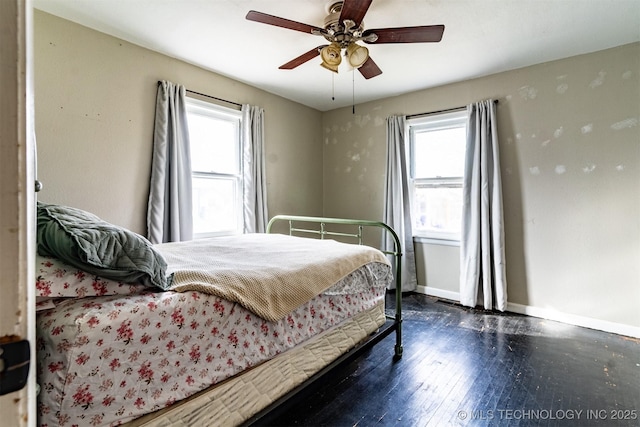 bedroom with ceiling fan, multiple windows, and dark hardwood / wood-style floors