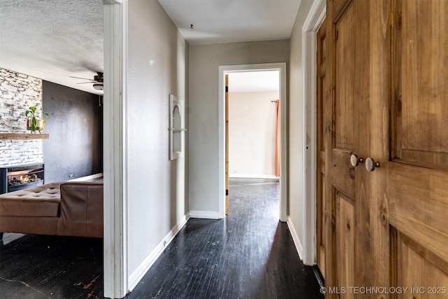 hallway with a textured ceiling and dark hardwood / wood-style flooring