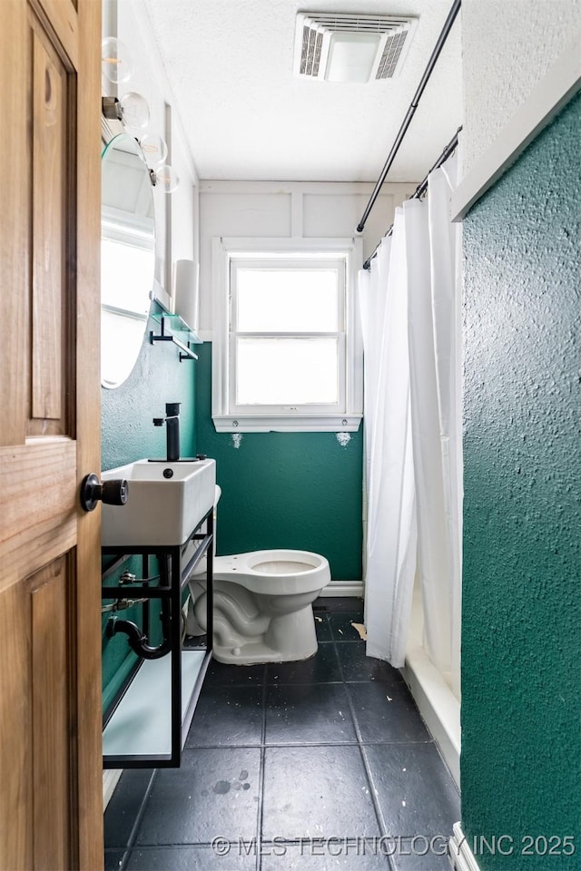 bathroom with toilet, sink, and a shower with shower curtain