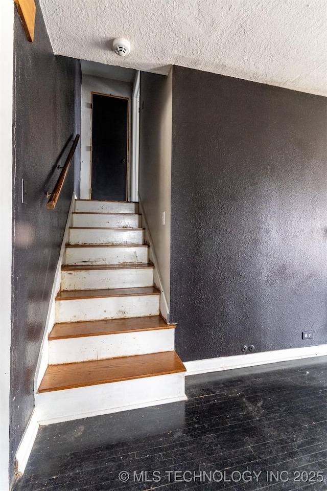 stairs featuring wood-type flooring and a textured ceiling