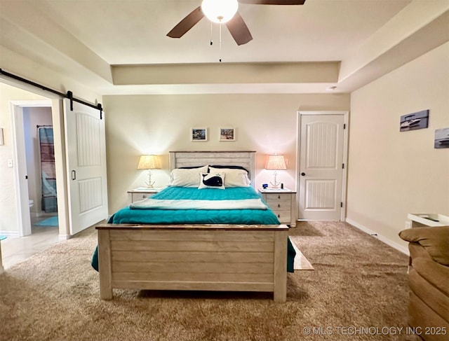 carpeted bedroom featuring ceiling fan, a raised ceiling, and a barn door