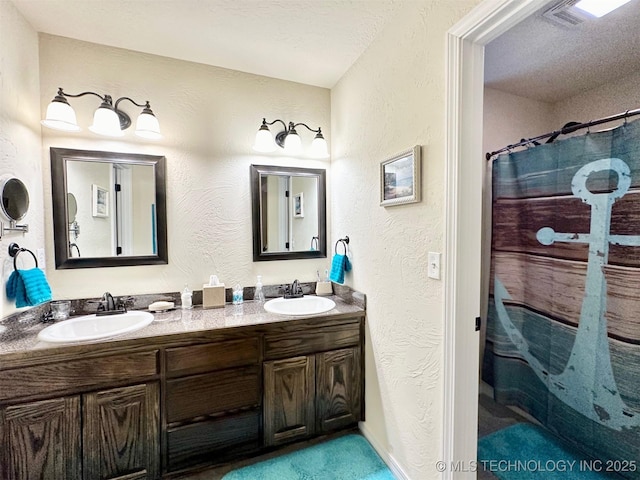 bathroom featuring a textured ceiling, walk in shower, and vanity