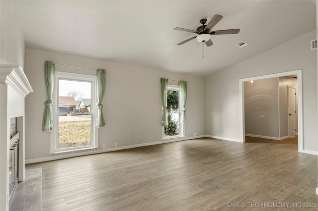 unfurnished room featuring hardwood / wood-style flooring, a wealth of natural light, lofted ceiling, and a fireplace