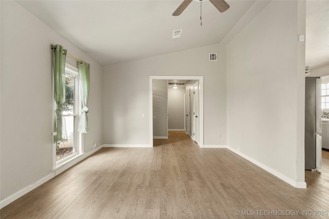 spare room featuring lofted ceiling, wood-type flooring, a wealth of natural light, and ceiling fan