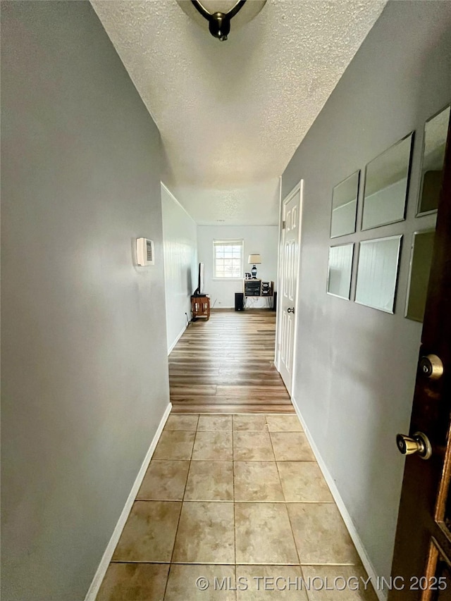 corridor featuring light tile patterned floors and a textured ceiling