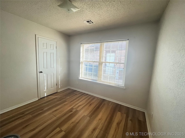 unfurnished room featuring dark wood-type flooring and a textured ceiling