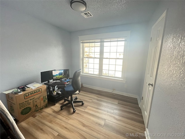 office space with light hardwood / wood-style floors and a textured ceiling